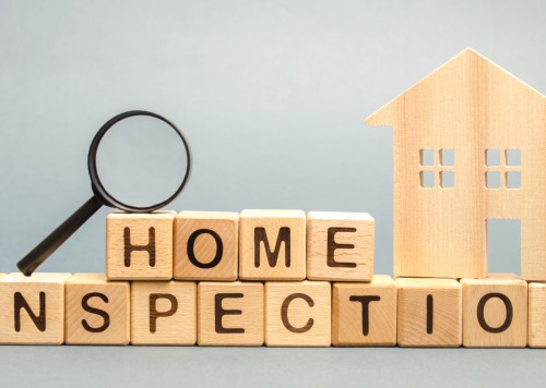 Wooden blocks with the word Home Inspection and the house. Resale residential property condition. The study of the state of the house associated with the sale of housing. Property valuation
