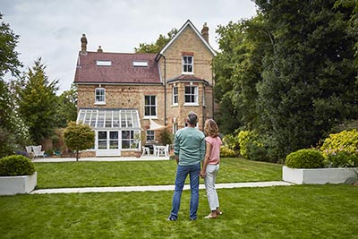 Rear view of couple on grass looking at house